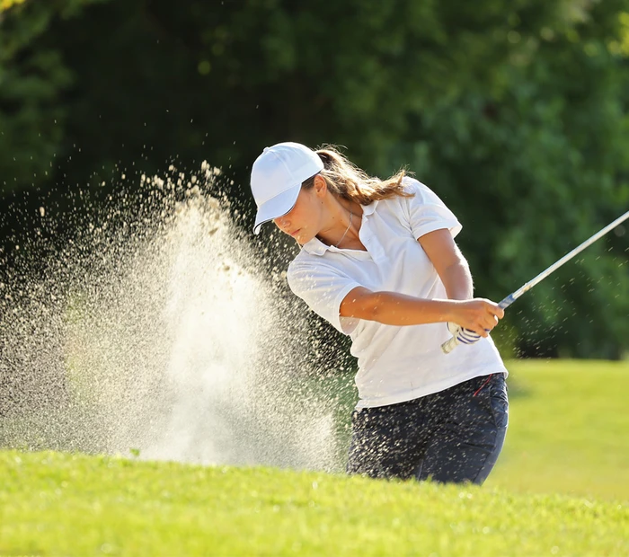 Golfspielerin beim Abschlag im Bunker