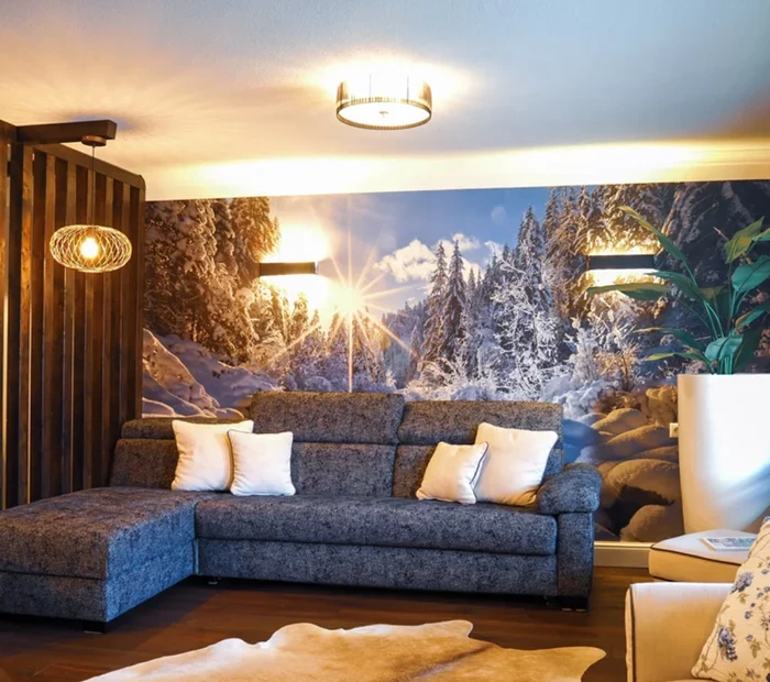 gemütliches großes Sofa vor einer Wand mit Bildtapete, die eine Winterlandschaft zeigt
