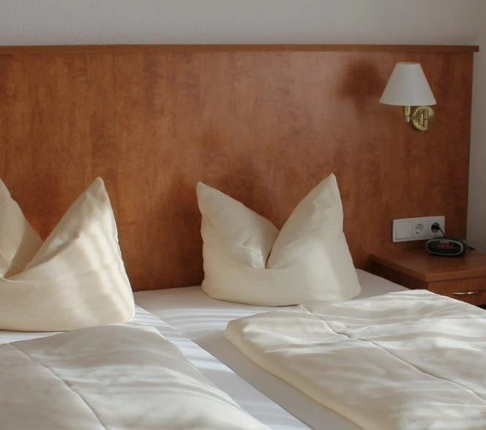 Doppelbett aufgebettet mit Nachtkästchen und Wandleuchte