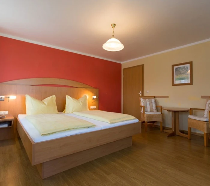 Doppelzimmer in warmen Tönen mit Doppelbett und Boden in Holzoptik