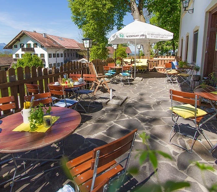 Auf der Sonnenterasse vom Hotel Alpenblick stehen im Biergartenstyle Tische und Stühle.