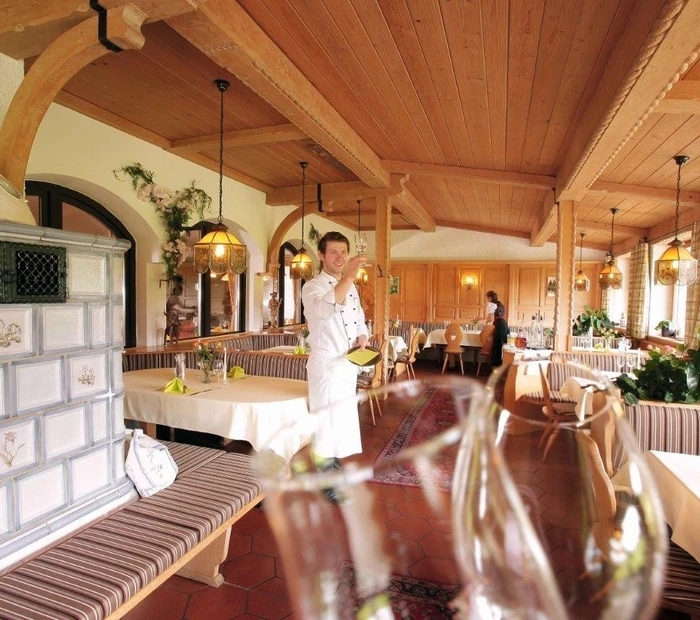 Restaurant mit Kachelofen und gemütlicher Ofenbank im Vordergrund