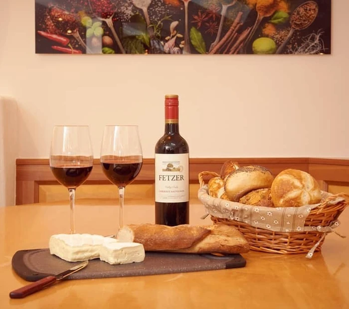 Wein mit Gläsern und Käseplatte für zwei Personen auf dem Esstisch