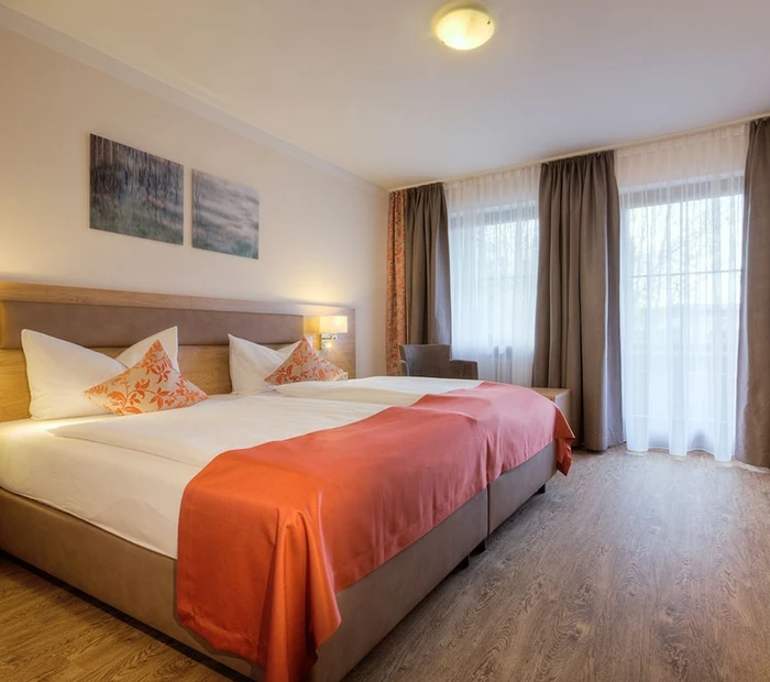 Doppelbett im Doppelzimmer Schlosssee in warmen Tönen mit Boden in Holzoptik