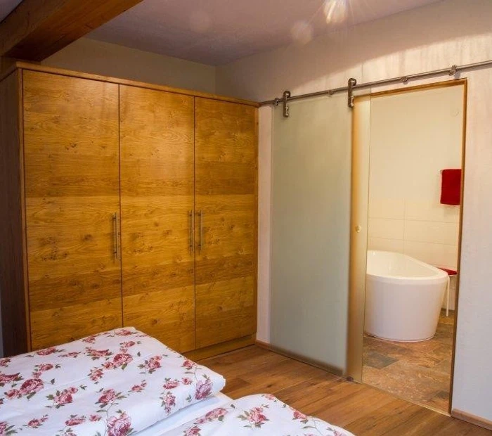 Schlafzimmer im Chalet Rotwild mit Blick auf die freistehende Badewanne im separaten Bad