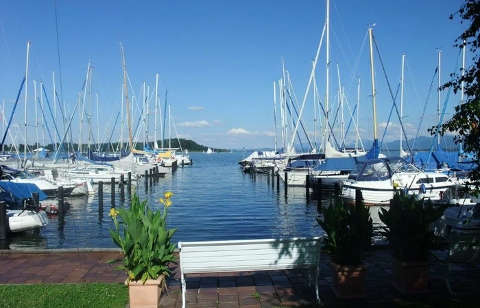 Zu sehen sind Segelboote die am Steg vom Yachthotel Chiemsee angelegt haben.