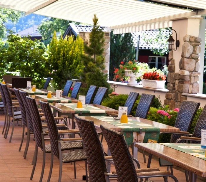 Schattige Gartenterrasse mit Tischen und Stühlen