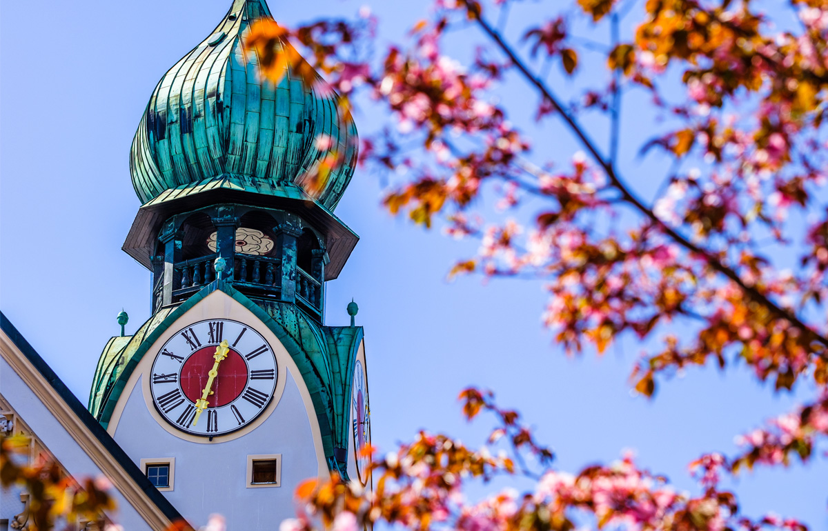 Blick auf einen alten Kirchturm mit Uhr in Rosenheim.