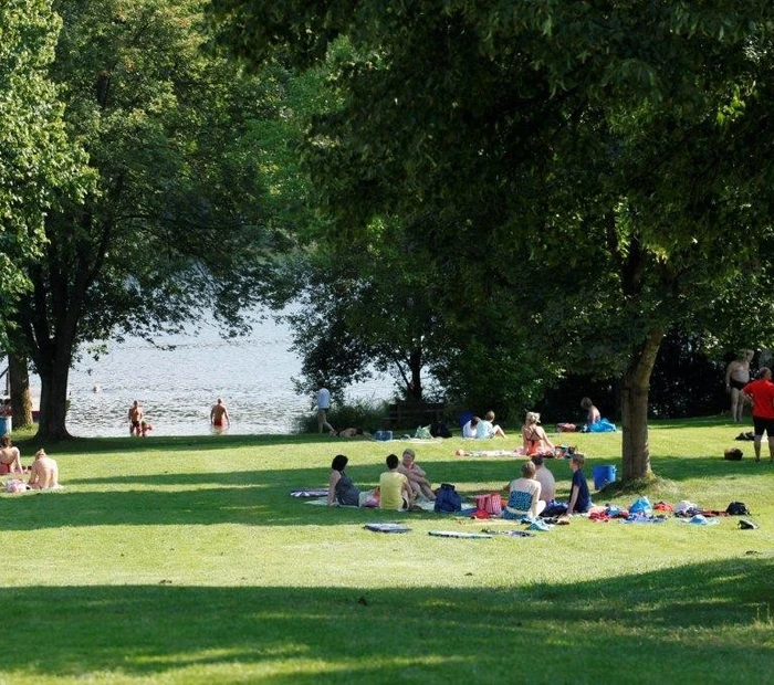 Menschen auf der Liegewiese am hauseigenen Badesee