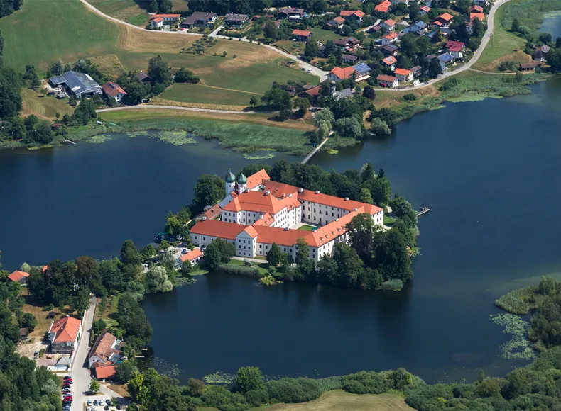 Sie sehen das Kloster und Schloss Seeon im See.