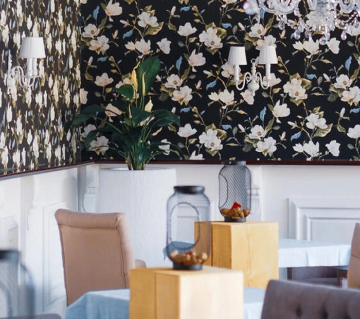 Tische in der Brasserie des Alpenliebe Designhotels vor floraler Tapete
