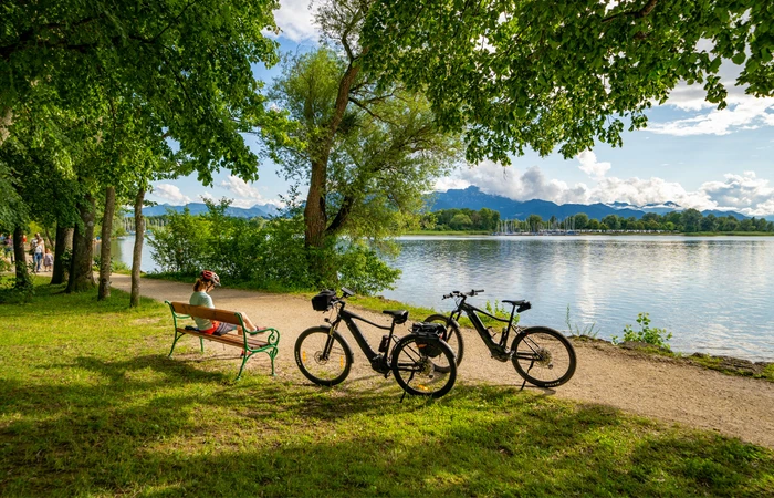 1 Radfahrerin sitzt auf einer Bank mit Blick auf den Chiemsee.