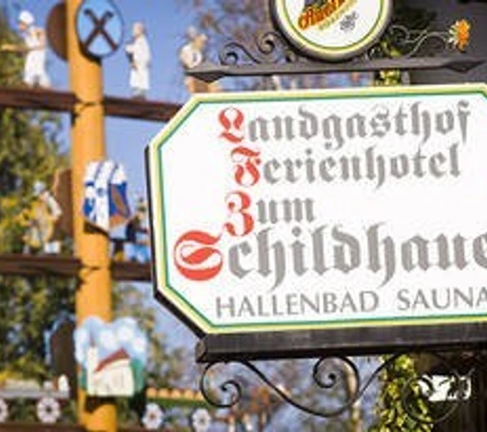 Wirtshausschild und im Hintergrund der Maibaum 