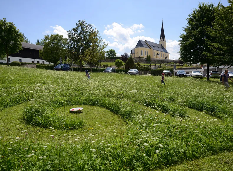 Dorfkiche und ein konzentrische außerirdischen Kreis im Rasen des Erdstahlenfeldes Bernau am Chiemsee.